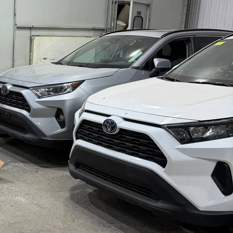 Deux Toyota RAV4, une grise et une blanche, garées dans l'entrepôt