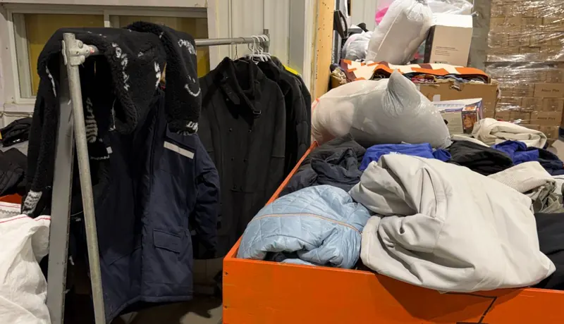 Manteaux sur un portant et vêtements en cours de tri dans un grand bac